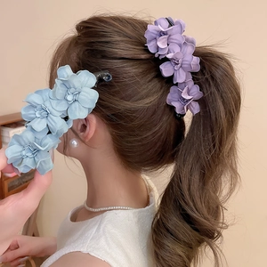 Vue détaillée de pinces banane fleurs 3D en acrylique mat violet et bleu sur cheveux
