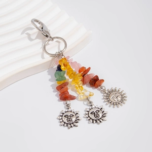 Detail view of colorful crushed stones and sun face charms on a silver metal keychain