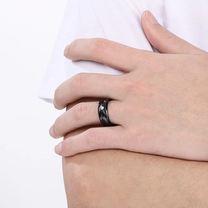 Detail of men's black feather textured ring with a centered diamond on hand