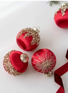 Detail of red satin Christmas ball with gold sequins and pearls on white background