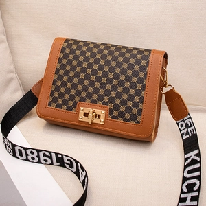 Retro geometric print crossbody bag with gold buckle and bicolor woven strap on a sofa
