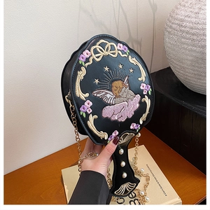 Detail of baroque embroidery with angel and floral motifs on a hand mirror shaped bag