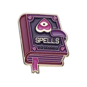 Macro shot of purple enamel magic book brooch with Spells lettering and gold trim