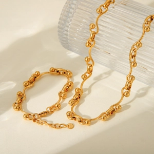 Detailed view of gold horseshoe buckle jewelry set featuring wave links and beads