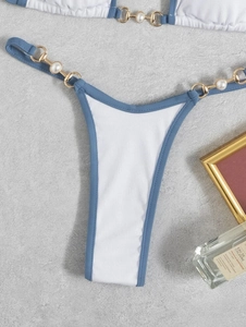 Detail of white ribbed bikini bottom with blue trim and gold pearl chain accents
