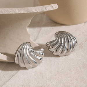 Macro shot of silver shell-textured stud earrings on a natural stone background