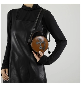 Detail of brown round PU leather crossbody bag with gothic metal cross and chain strap