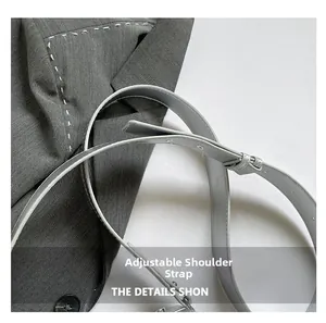 Detail of adjustable light gray shoulder strap with contrasting white stitching on a bag