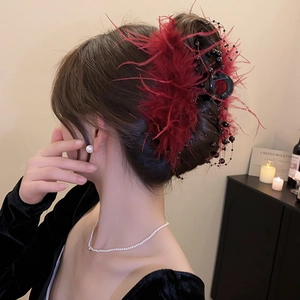 Detailed view of burgundy feather hair claw clip with beads for elegant hairstyles