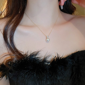 Close-up of minimalist pearl and zircon pendant necklace on a female neck