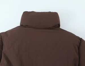 Detailed close-up of dark brown puffer jacket stand-up collar and shoulder stitching