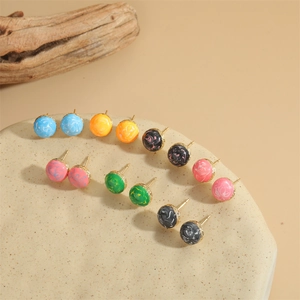 Minimalist round bead earrings in various colors on a ceramic display with branches