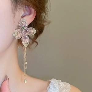 Primo piano di una modella che indossa orecchini a fiore intrecciato con frange e gocce verdi