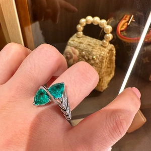 Macro detail of Toi et Moi ring with dual green triangle stones and pave diamond band