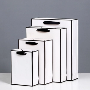 Minimalist white paper gift bags with black borders and handles in four varied sizes