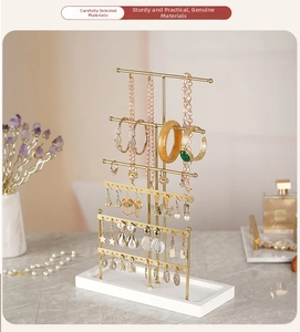 Detail of 6-tier gold metal jewelry stand with necklace hooks and white base tray