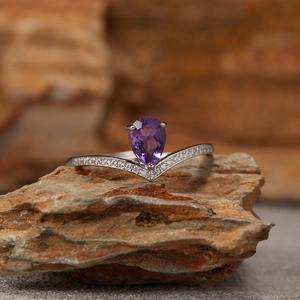 Macro shot of V-shaped S925 silver ring with pear-cut amethyst and sparkling zircon pavé