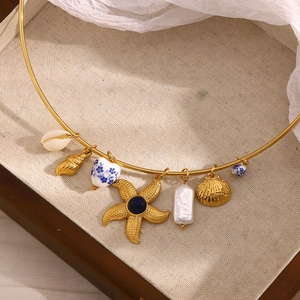 Detail of 18K gold plated necklace with starfish, shell, pearl and ceramic heart charms