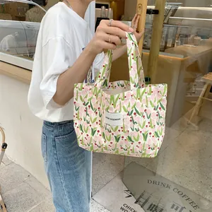 Détail du sac cabas en toile avec imprimé tulipes roses et étiquette de marque tissée