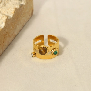 Detailansicht eines Goldrings mit Malachit und Tigerauge-Steinen auf Steinhintergrund