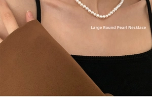 Close-up of large oval freshwater pearls worn against a black knit garment