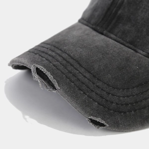Dettaglio della visiera consumata con bordi sfrangiati su un cappello di cotone lavato
