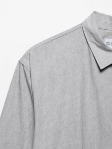 Detailed close-up of grey shirt collar and shoulder stitching with fine textured fabric
