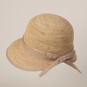 Detailed view of the woven raffia sun hat texture with elegant bow and cloche ribbon trim