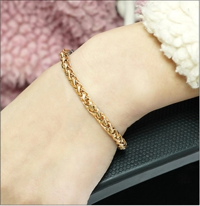 Detail of 18K gold plated stainless steel wheat chain bracelet on a person wrist