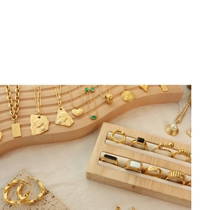 Elegant gold jewelry set with necklaces and gemstone rings displayed on wooden stands