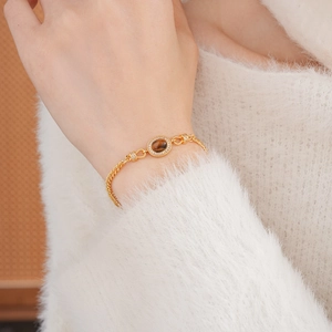 Close-up of gold-plated bracelet with oval tiger eye stone and shimmering accents