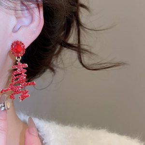 Detail of red Chinese character Xi earrings with crystals in gold finish on a model