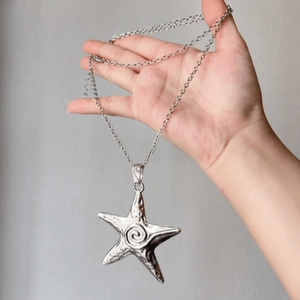 Macro detail of silver starfish pendant necklace featuring a rustic spiral texture