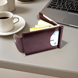 Dark brown leather wallet with metal buckle on desk featuring cards and cash storage