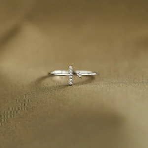 Detailed close-up of S925 silver T-shape ring with pavé zircons on green silk fabric