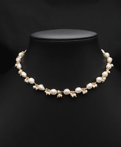 Close-up of baroque pearl necklace with gold chain on a black velvet mannequin display