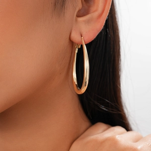 Close-up of elegant gold-tone U-shaped earrings worn by model with a polished smooth finish
