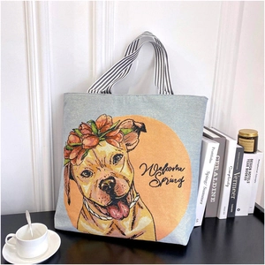 Detail of canvas tote bag with dog print and black white striped handles on a desk