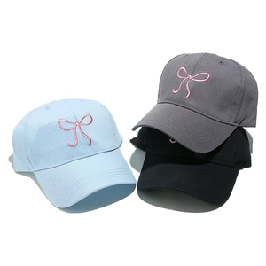 Three cotton baseball caps in blue, grey, and black with pink bow embroidery detail