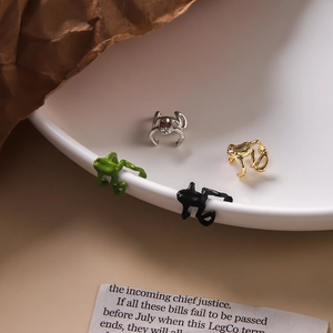 Bagues d'oreilles grenouille punk en vert, noir, or et argent sur un plateau blanc