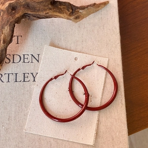 Close-up of vintage red geometric round hoop earrings on a rustic linen and book background
