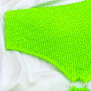 Close-up of neon green seersucker swimsuit fabric with a stylish silver metal ring detail
