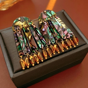 Macro detail of iridescent colorful shell tassel drop earrings on black jewelry box