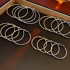 Set of gold and silver hoop earrings in various sizes on a brown leather texture tray