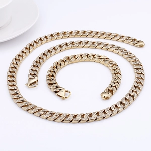 Gros plan d'un ensemble collier et bracelet maille cubaine dorée serti de strass brillants