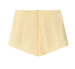 Close-up of light yellow satin shorts with smooth texture and hidden zipper detail