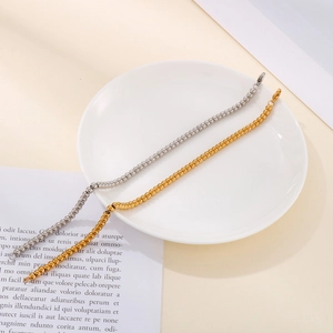 Detailed view of silver and gold stainless steel 4mm bead bracelets on ceramic plate