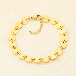 Detailed shot of gold plated disc bracelet with adjustable chain on textured fabric