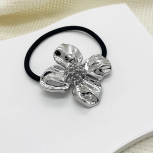 Macro detail of silver alloy flower hair tie with textured petals and elastic black band