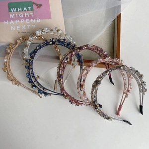 Detail of five woven crystal and pearl headbands in various colors on white silk